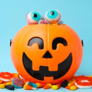 Image of an orange Jack-o'-lantern treat bucket full of lollies. 