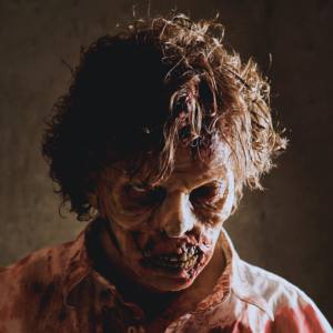 Image of a man dressed as a zombie wearing special effects prosthetics and makeup.
